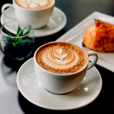 A cappuccino on a table with a pastry next to it